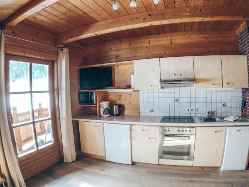 a kitchen with white cabinets and a large window at Cozy holiday apartment close to the slopes in Kleinarl