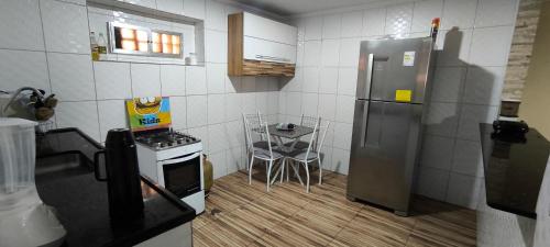 a kitchen with a stainless steel refrigerator and a table at Casa com garagem no coração de Arraial! in Arraial do Cabo