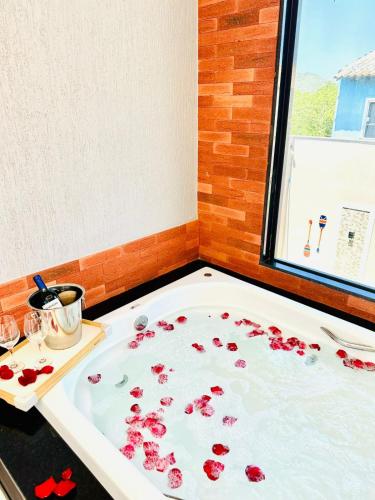 a bath tub filled with red flowers in a bathroom at Pousada Amaral Búzios in Búzios