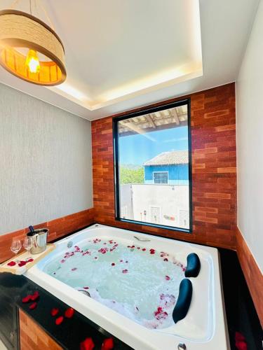 a jacuzzi tub in a room with a window at Pousada Amaral Búzios in Búzios