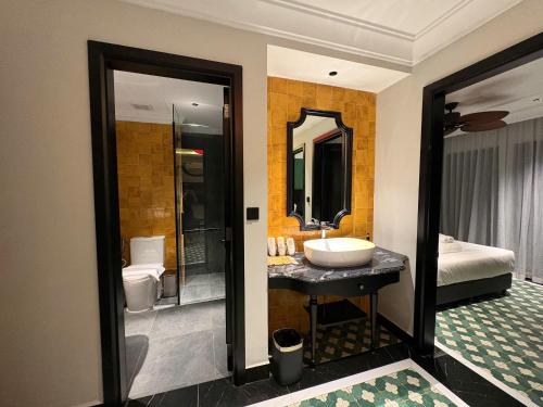 a bathroom with a sink and a bed and a mirror at L'Heritage Riverside Hoi An in Hoi An