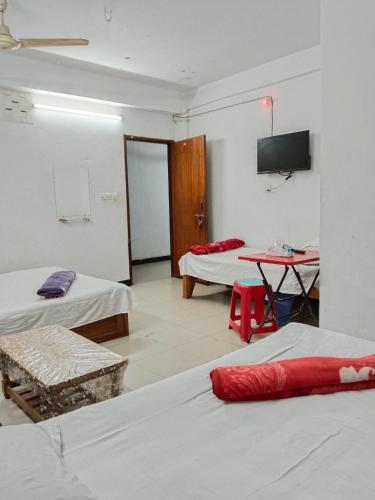 a room with two beds and a table and a tv at Hotel Rose International in Dhaka