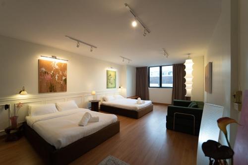 a hotel room with two beds and a couch at Roni House Thonglor in Bangkok