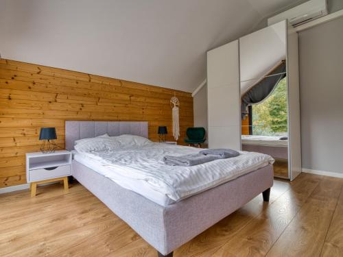 a bedroom with a large bed and a wooden wall at Dom przy lesie in Wielgie