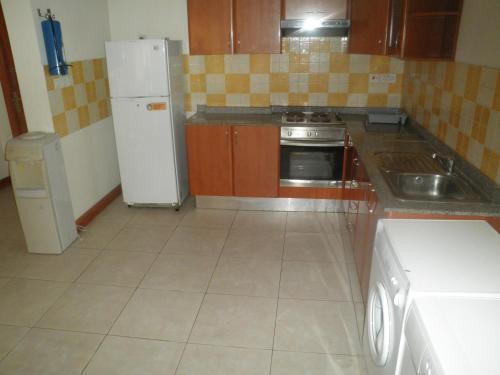 a kitchen with a white refrigerator and a stove at Desert Pearl Hotel Apartment in Manama
