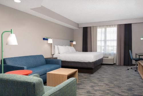 a hotel room with a bed and a couch and chair at Garner Hotel Evansville East by IHG in Evansville