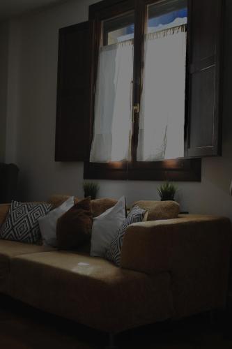 a couch sitting in a living room with a window at Villa Rosa Canfranc, tu refugio en el corazón del Pirineo Aragonés in Canfranc