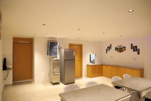 a kitchen with a refrigerator and tables and chairs at Hotel Pine View in Rajkot