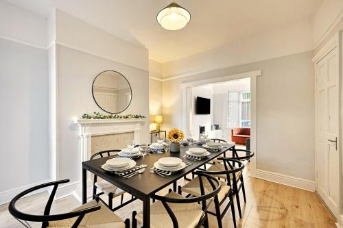 Un comedor con una mesa y sillas y un espejo. en Balfour House - Air Host & Stay - Sleeps 8, free parking, en Litherland