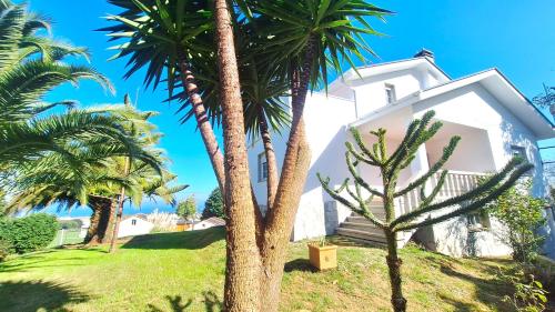 a white house with palm trees in front of it at Casa Naveira vistas mar en Foz in Foz