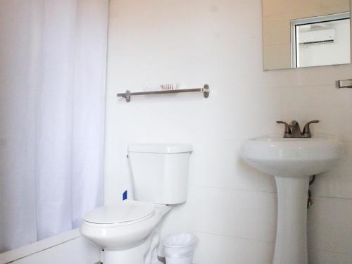 Un baño blanco con inodoro y lavabo. en Villas at Auxilio Mutuo 106, en San Juan