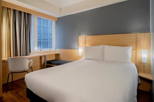 a hotel room with a bed and a chair at ibis Sao Paulo Paulista in Sao Paulo