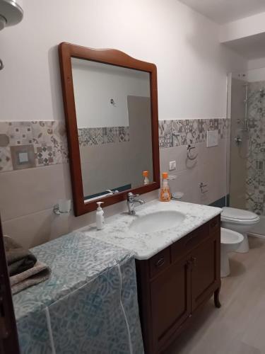 Un baño con lavabo, espejo e inodoro. en Dolce Rifugio, en Siculiana