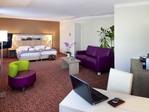 a hotel room with a bed and a desk with a laptop at Mercure Hotel Hamburg am Volkspark in Hamburg