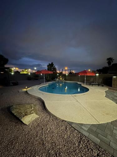 a swimming pool at night with umbrellas on a patio at Heated Pool, Hot Tub, Games & more! in Mesa