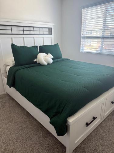 a white bed with a teddy bear sitting on it at North Fontana pool house in Fontana