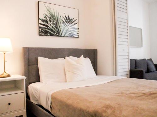 a bedroom with a bed with white pillows and a chair at Villas at Auxilio Mutuo 103 in San Juan