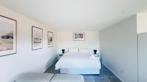a white bedroom with a bed and a couch at KINGI Granny Flat in Batemans Bay