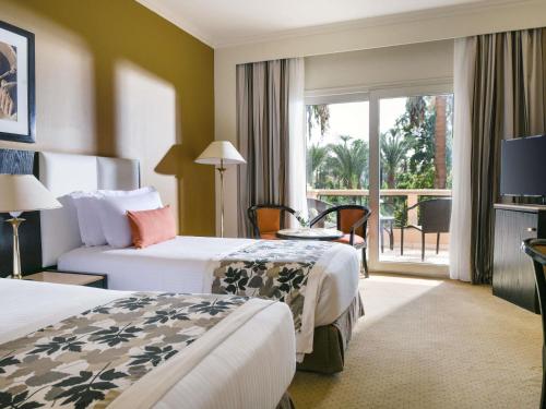 a hotel room with two beds and a balcony at Pavillon Winter Luxor in Luxor
