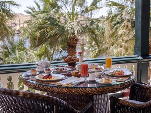 uma mesa com comida numa varanda com palmeiras em Sofitel Legend Old Cataract em Aswan