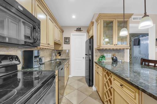 a kitchen with wooden cabinets and a black refrigerator at Driftwood Days Pet Friendly Beach Home in Myrtle Beach