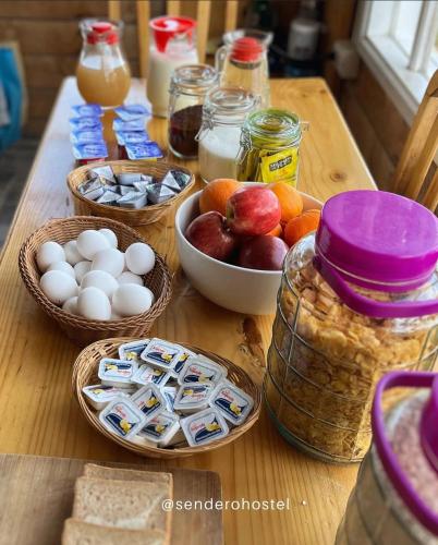 Una mesa de madera con huevos, pan y fruta sobre ella. en El Sendero, en Puerto Natales