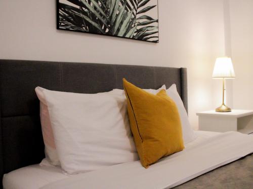 a bed with white and yellow pillows and a lamp at Villas at Auxilio Mutuo 102 in San Juan