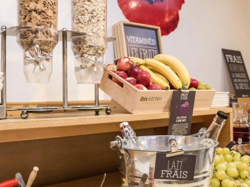 Un mostrador con un bol de fruta y una caja de frutos secos. en ibis Saint Brieuc Yffiniac, en Yffiniac