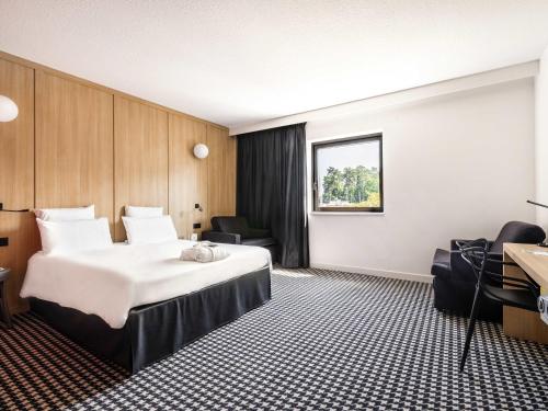 ジュエ・レ・トゥールにあるMercure Tours Sudの大きなベッドと机があるホテルの部屋