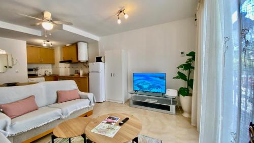 a living room with a white couch and a tv at Brisas de Guadalest in El Castell de Guadalest