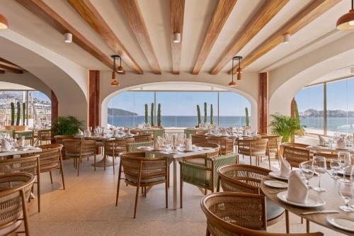 a restaurant with tables and chairs and a view of the ocean at Fiesta Americana Acapulco Villas in Acapulco