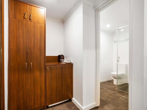 a bathroom with a wooden cabinet and a toilet at Ibis Styles Karratha in Karratha