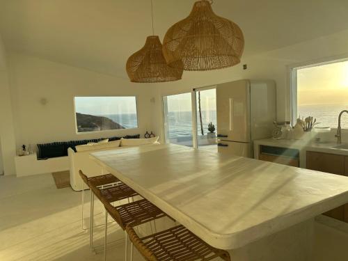 a kitchen and living room with a large white table at Casa da Praia Valmitão in Ribamar