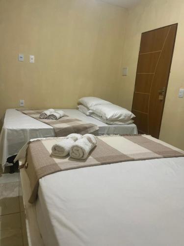 three beds in a room with towels on them at Pousada Alto do Tambá in São Francisco