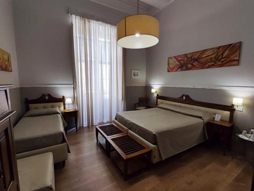 un dormitorio con dos camas y un sofá en La Collegiata Guest House, en Catania