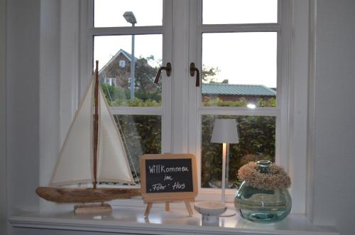 ein Fensterbrett mit einem Schild und einem Segelboot darauf in der Unterkunft Hardesweg 63 Nr 3 in Boldixum