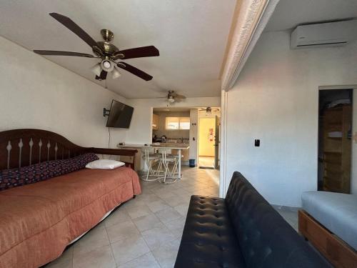 a bedroom with a couch and a ceiling fan at Suite Villas Palmas Diamante in Acapulco