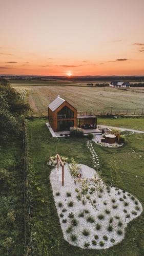 a house in a field with the sunset in the background at Okno Na Ślężę in Sady