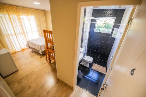 une salle de bain avec douche et toilettes dans une chambre dans l'établissement Pousada San Jose, à Pântano Grande