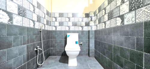 a bathroom with a toilet in a green tiled wall at Avante Palace in Rānchī