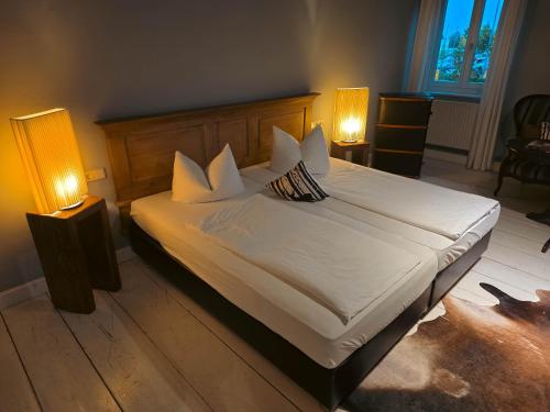 a bedroom with a large white bed with two lamps at Gasthof Staudham in Wasserburg am Inn