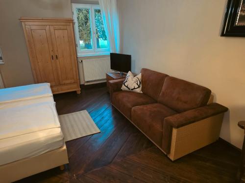 a living room with a brown couch and a television at Gasthof Staudham in Wasserburg am Inn