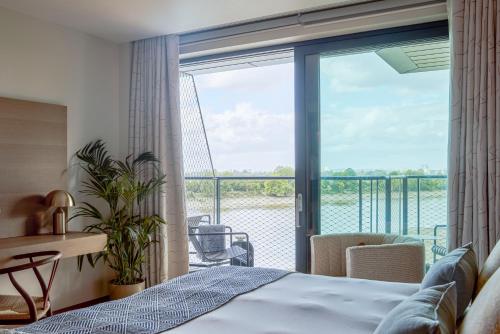 Un dormitorio con una cama y un balcón. en Fulham Pier Hotel, en Londres