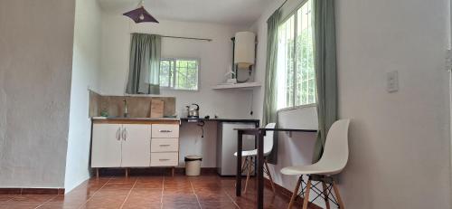 a kitchen with white cabinets and a table and chairs at Apart Sierras Chicas in Río Ceballos