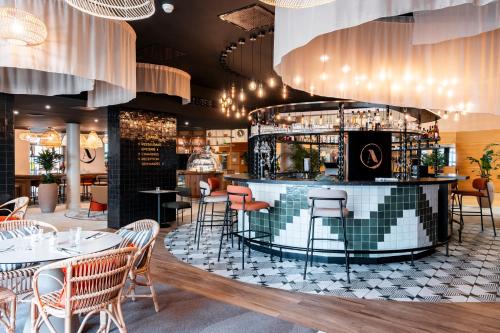 ein Restaurant mit einer Bar mit Tischen und Stühlen in der Unterkunft Novotel Belfort Centre Atria in Belfort