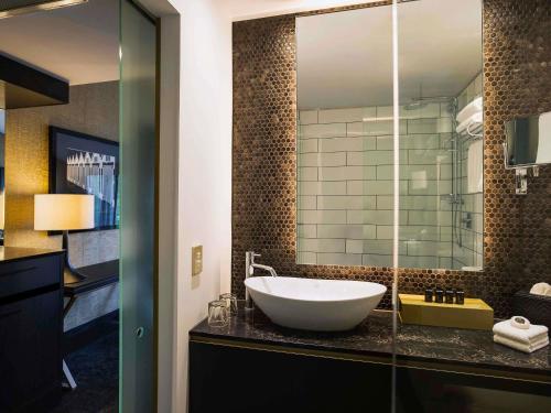a bathroom with a sink and a large mirror at Mövenpick Hotel Wellington in Wellington