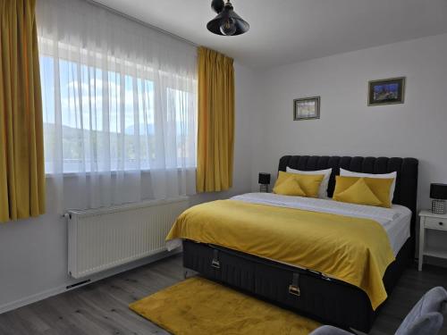 a bedroom with a bed with yellow sheets and a window at Penthouse Râșnov 80mp, balcon 30mp in Râşnov