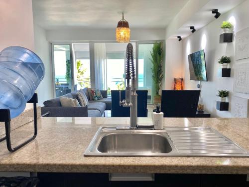 una encimera de cocina con fregadero y una sala de estar. en Cozy Beach Front Condo, Pool, en La Puntica de Juan Dolio