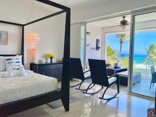 Un dormitorio con una cama y un escritorio y vista al mar. en Cozy Beach Front Condo, Pool, en La Puntica de Juan Dolio