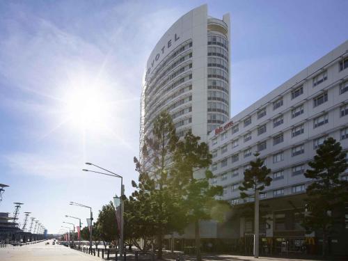 a tall white building with the sun behind it at Novotel Sydney Olympic Park in Sydney